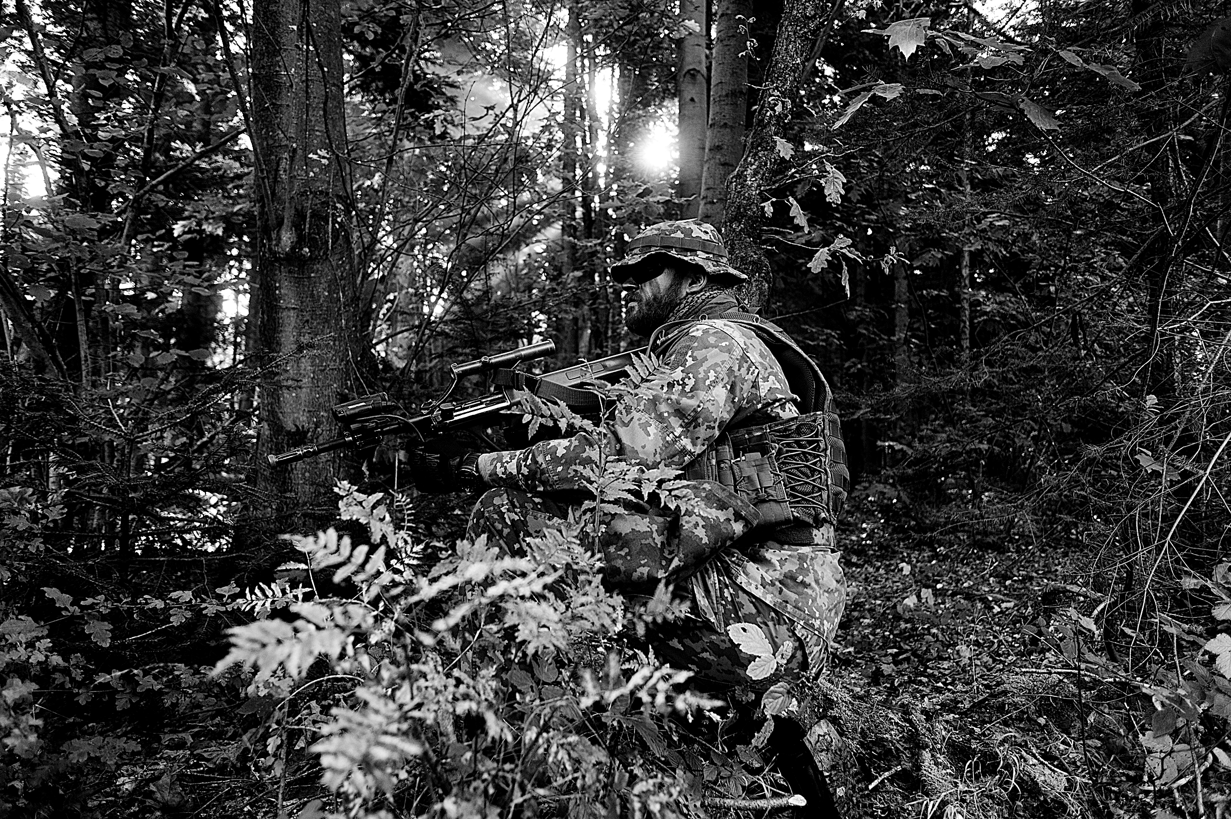Ein bewaffneter Soldat hat in einem Wald Stellung bezogen
